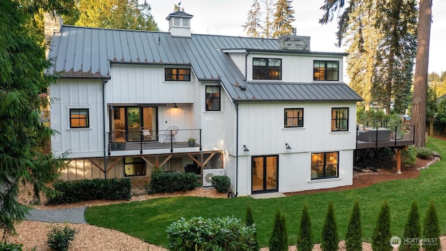 back of house with metal roof, a yard, a chimney, and a standing seam roof