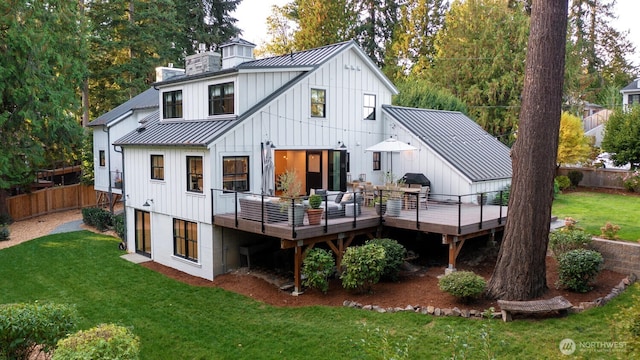 rear view of property with a lawn, fence, metal roof, a wooden deck, and a standing seam roof