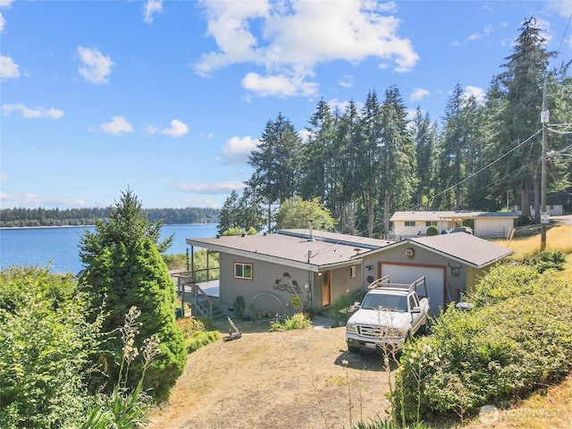 71 E Mountain Dr, Grapeview, WA 98546 - view of front of house featuring a water view, dirt driveway, an attached garage, and stairs
