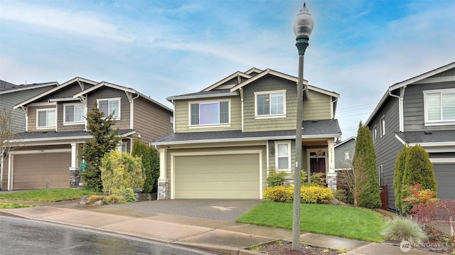 craftsman-style house featuring stone siding, a front lawn, driveway, and a garage