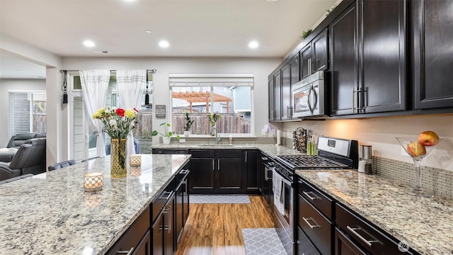 kitchen featuring a wealth of natural light, a sink, light wood-style floors, and appliances with stainless steel finishes