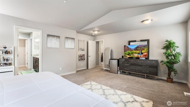 bedroom with baseboards, vaulted ceiling, light colored carpet, and ensuite bathroom
