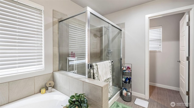 full bathroom with a bath, baseboards, plenty of natural light, and a stall shower