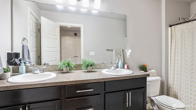 bathroom featuring tasteful backsplash, double vanity, toilet, and a sink