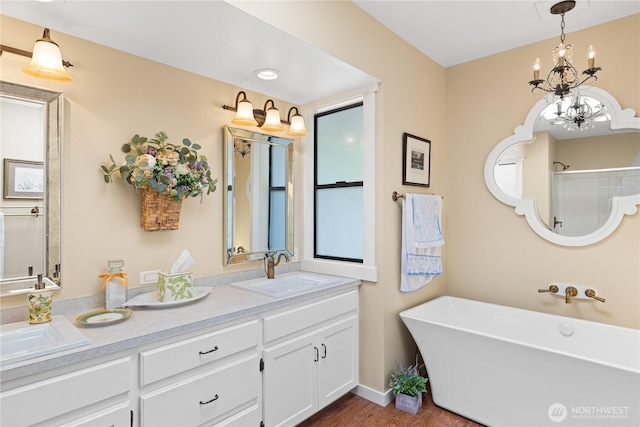 full bathroom featuring a sink, an inviting chandelier, walk in shower, double vanity, and a freestanding bath