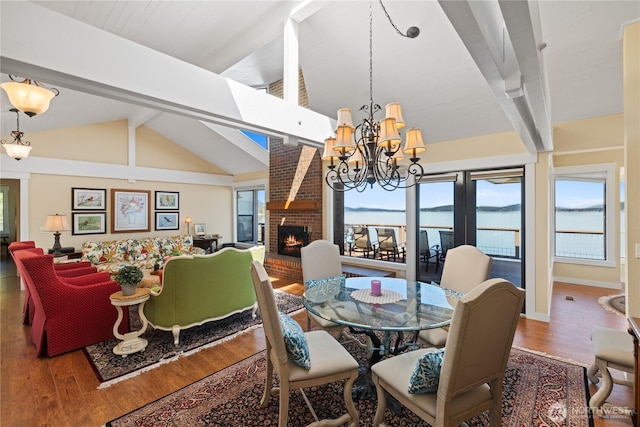dining room with lofted ceiling with beams, a chandelier, wood finished floors, and a fireplace