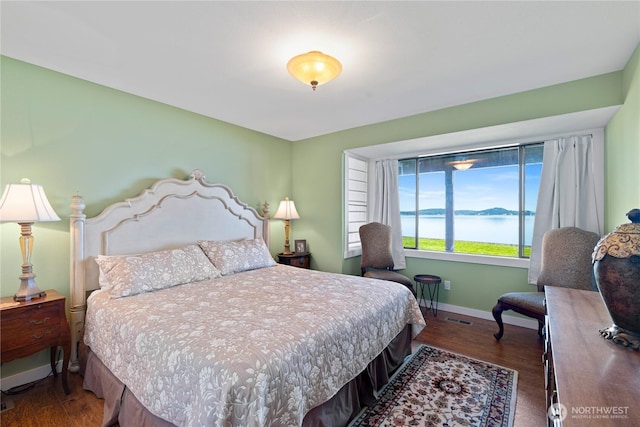 bedroom with visible vents, wood finished floors, baseboards, and a water view