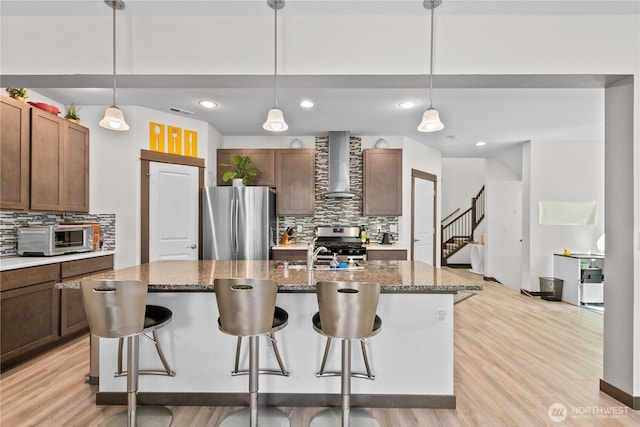 17431 3rd Ave SE, Bothell, WA 98012 - kitchen with appliances with stainless steel finishes, wall chimney exhaust hood, backsplash, a breakfast bar, and light wood-style flooring