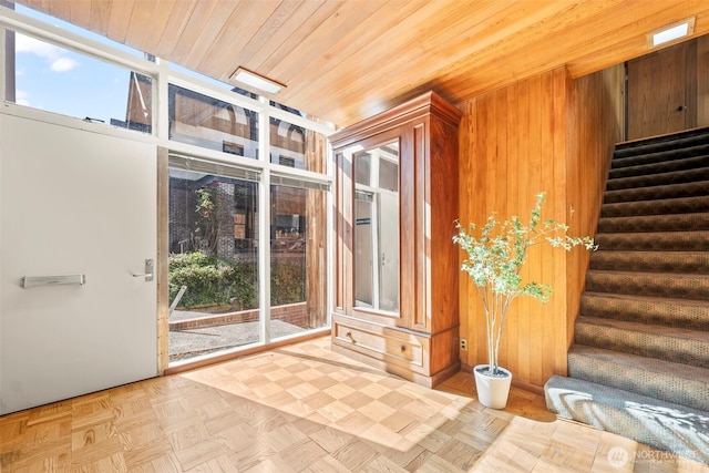 entryway featuring stairs, wooden walls, and wooden ceiling