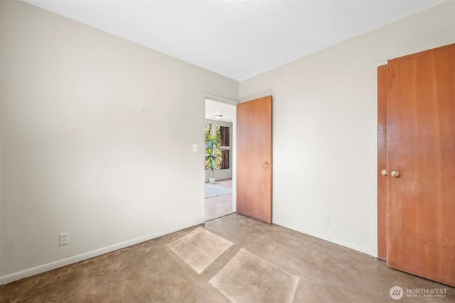unfurnished bedroom with baseboards and concrete flooring