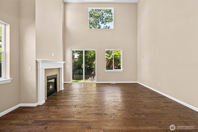 2126 Olivia St SE, Olympia, WA 98513 - unfurnished living room with healthy amount of natural light, a high ceiling, a glass covered fireplace, and dark wood-type flooring
