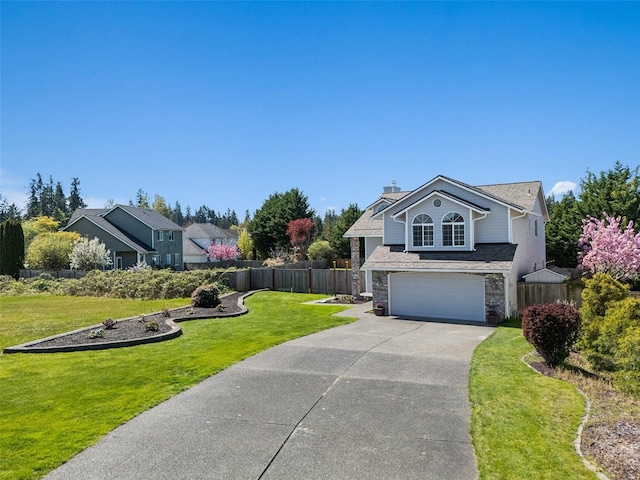 view of front of property with a front lawn, driveway, a chimney, fence, and an attached garage