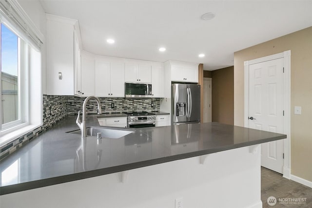 2734 Thornhill Rd SE, Puyallup, WA 98374 - kitchen featuring appliances with stainless steel finishes, a sink, a peninsula, dark countertops, and wood finished floors