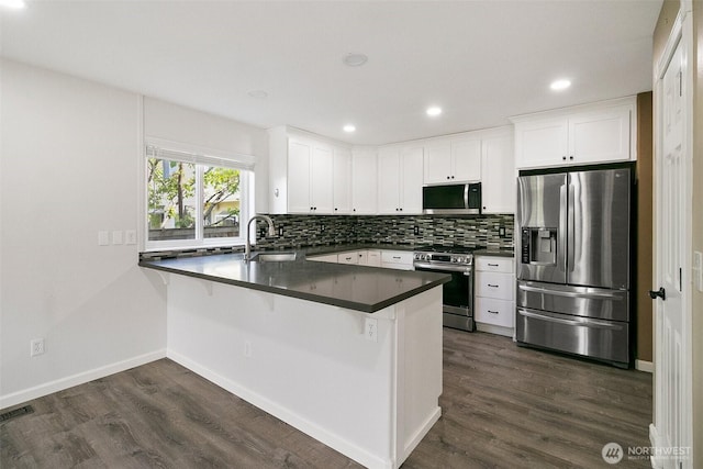 2734 Thornhill Rd SE, Puyallup, WA 98374 - kitchen featuring stainless steel appliances, a sink, dark countertops, a peninsula, and tasteful backsplash