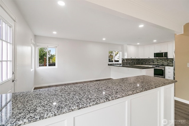 2734 Thornhill Rd SE, Puyallup, WA 98374 - kitchen with appliances with stainless steel finishes, dark wood-type flooring, white cabinetry, decorative backsplash, and dark stone countertops