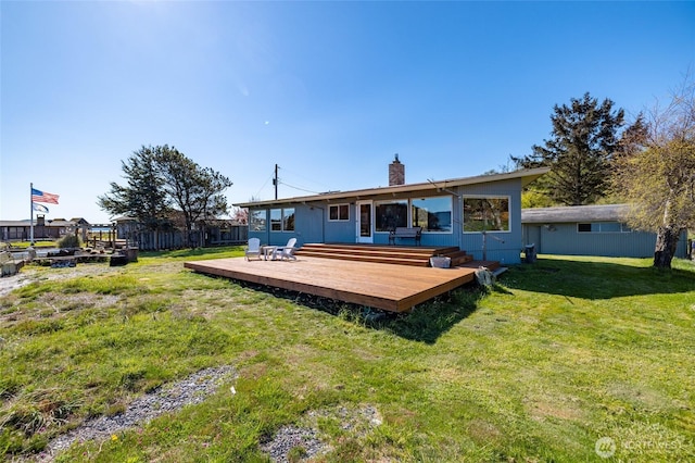 rear view of property featuring a chimney, fence, a deck, and a lawn