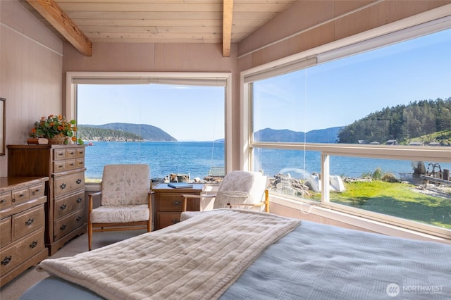 bedroom with lofted ceiling with beams, a water and mountain view, and multiple windows