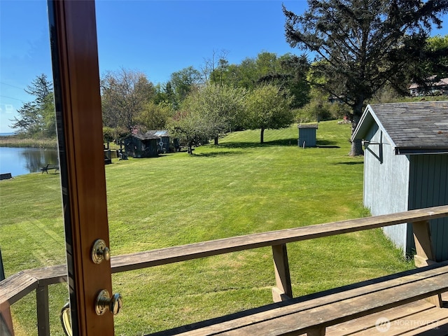 view of yard featuring an outbuilding, a shed, and a water view