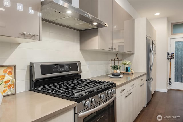kitchen with light countertops, appliances with stainless steel finishes, decorative backsplash, and wall chimney exhaust hood