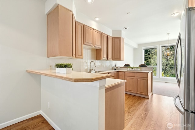 9821 NE Riverbend Dr Unit C102, Bothell, WA 98011 - kitchen featuring freestanding refrigerator, a peninsula, a sink, light wood-style floors, and light countertops