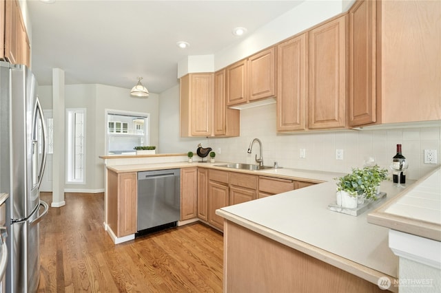 9821 NE Riverbend Dr Unit C102, Bothell, WA 98011 - kitchen featuring appliances with stainless steel finishes, a peninsula, a sink, light wood finished floors, and decorative backsplash