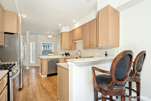 9821 NE Riverbend Dr Unit C102, Bothell, WA 98011 - kitchen with appliances with stainless steel finishes, a peninsula, light wood-type flooring, light countertops, and light brown cabinets