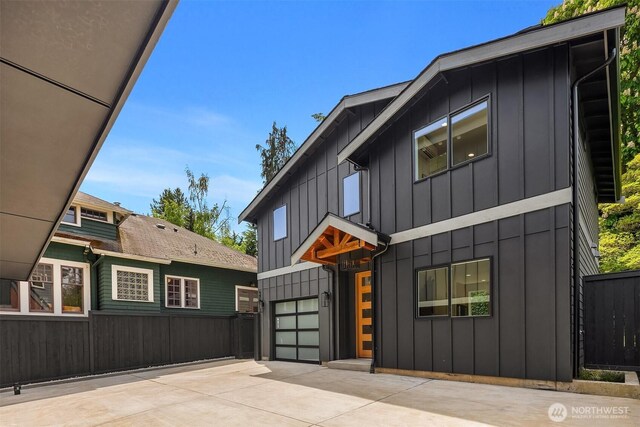 view of front of property with board and batten siding, fence, concrete driveway, and an attached garage