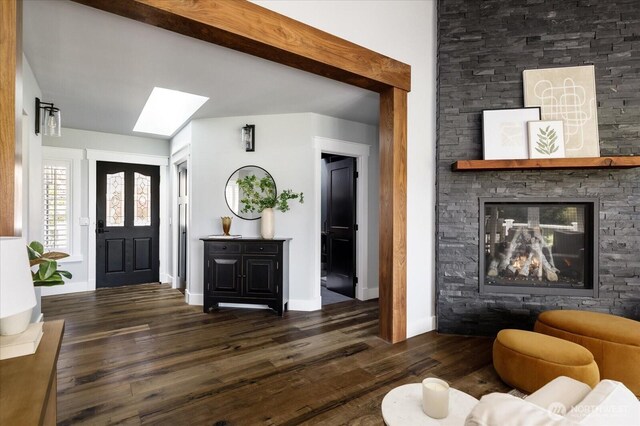 living room featuring a skylight, baseboards, wood finished floors, and a fireplace