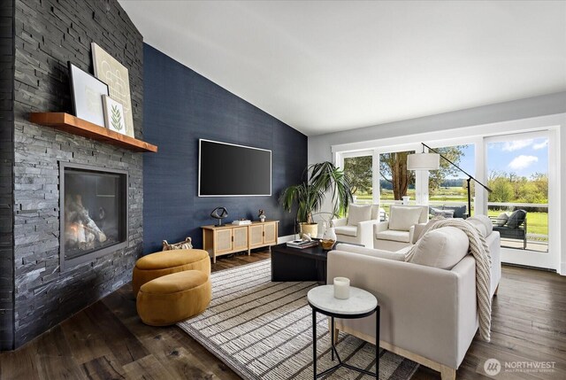 living room with vaulted ceiling, wood finished floors, an accent wall, and a fireplace