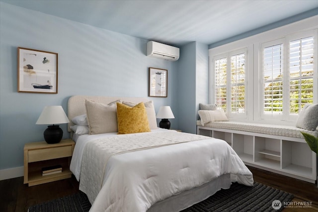bedroom featuring baseboards, dark wood-type flooring, and a wall mounted air conditioner