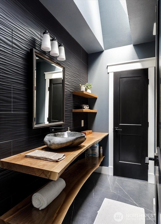 bathroom featuring baseboards, a sink, and marble finish floor