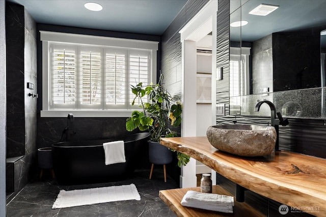 bathroom with a soaking tub, visible vents, marble finish floor, and a sink