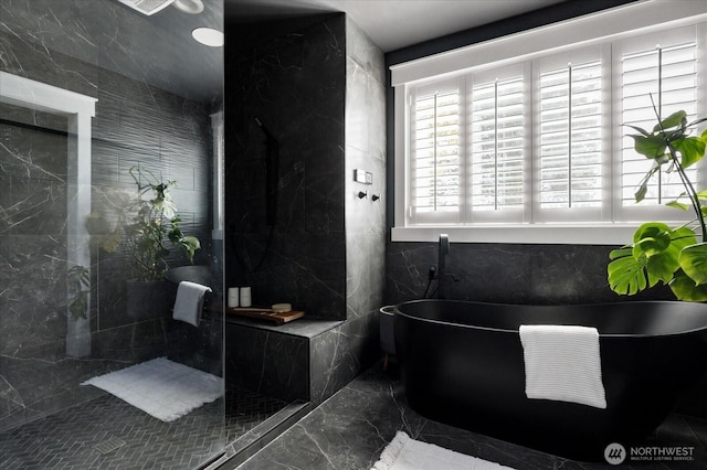 bathroom with a soaking tub, marble finish floor, and a walk in shower