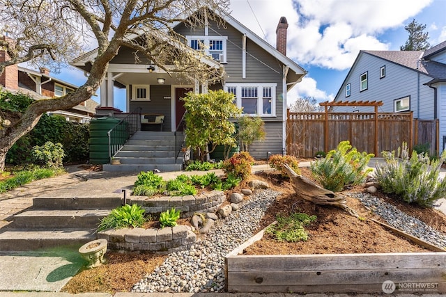 view of front of home with a chimney, fence, stairway, and covered porch