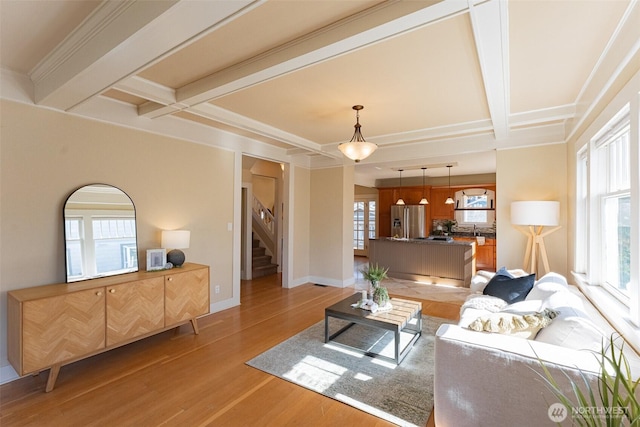 living room with light wood-style flooring, baseboards, coffered ceiling, beamed ceiling, and stairway