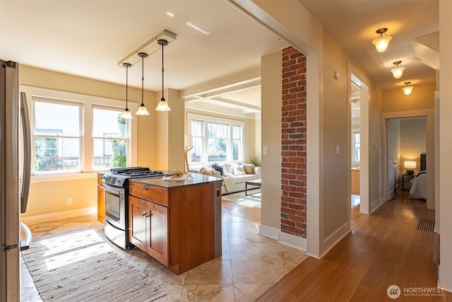 kitchen with stainless steel appliances, dark stone counters, baseboards, brown cabinetry, and hanging light fixtures