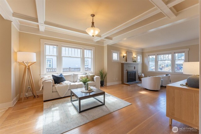 living room featuring a brick fireplace, baseboards, ornamental molding, and coffered ceiling