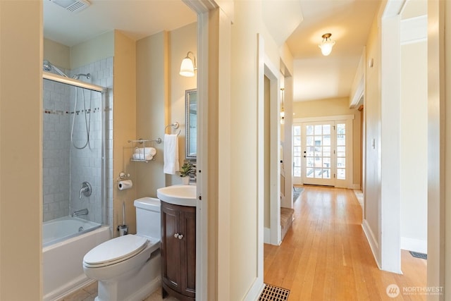 full bath featuring toilet, visible vents, wood finished floors, vanity, and tub / shower combination