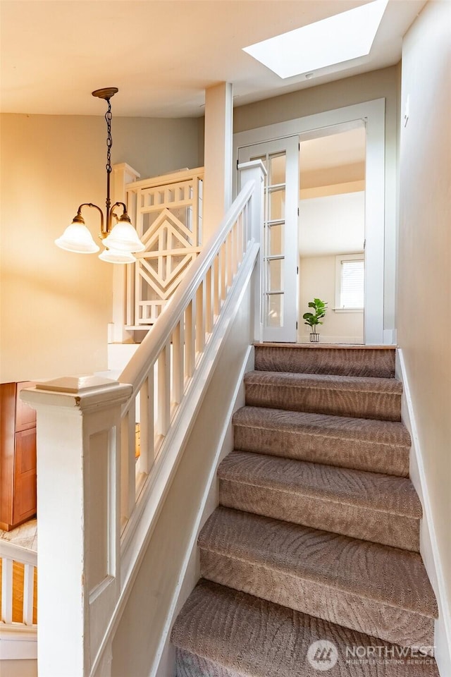 staircase with an inviting chandelier and a skylight