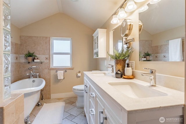bathroom with lofted ceiling, a freestanding tub, and a sink