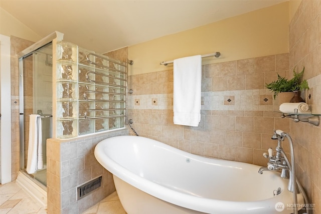 bathroom featuring a freestanding bath, tile walls, visible vents, and a stall shower