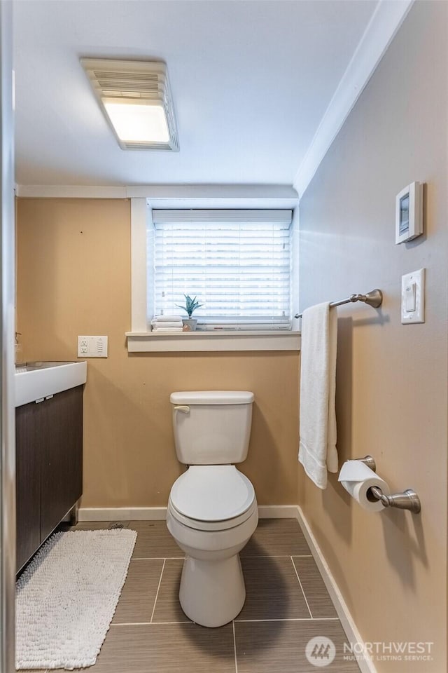half bathroom featuring vanity, toilet, tile patterned flooring, and baseboards