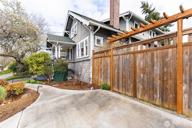 view of side of property featuring a patio area, a chimney, and fence