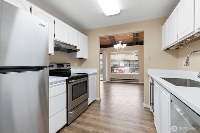 kitchen with a notable chandelier, appliances with stainless steel finishes, a sink, a baseboard radiator, and under cabinet range hood