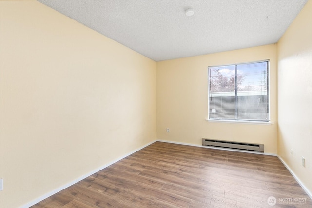 unfurnished room with baseboards, a baseboard radiator, a textured ceiling, and wood finished floors