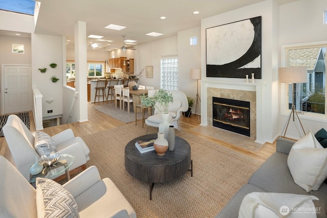 living room with light wood-style floors, healthy amount of natural light, a fireplace, recessed lighting, and a skylight
