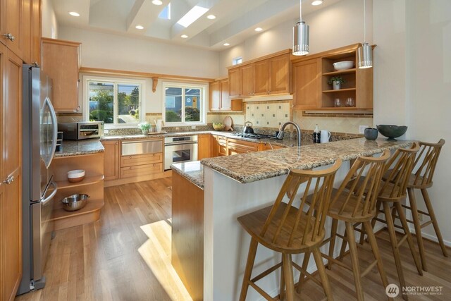 kitchen featuring stainless steel appliances, a peninsula, open shelves, light wood-type flooring, and decorative backsplash