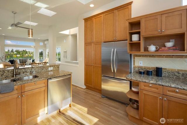 kitchen featuring appliances with stainless steel finishes, open shelves, a skylight, light wood-style floors, and a ceiling fan