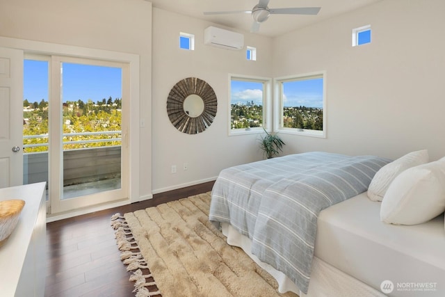 bedroom featuring a wall unit AC, access to outside, wood finished floors, baseboards, and a ceiling fan