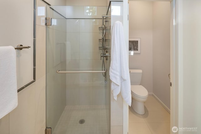 bathroom with toilet, a shower stall, tile patterned flooring, and baseboards
